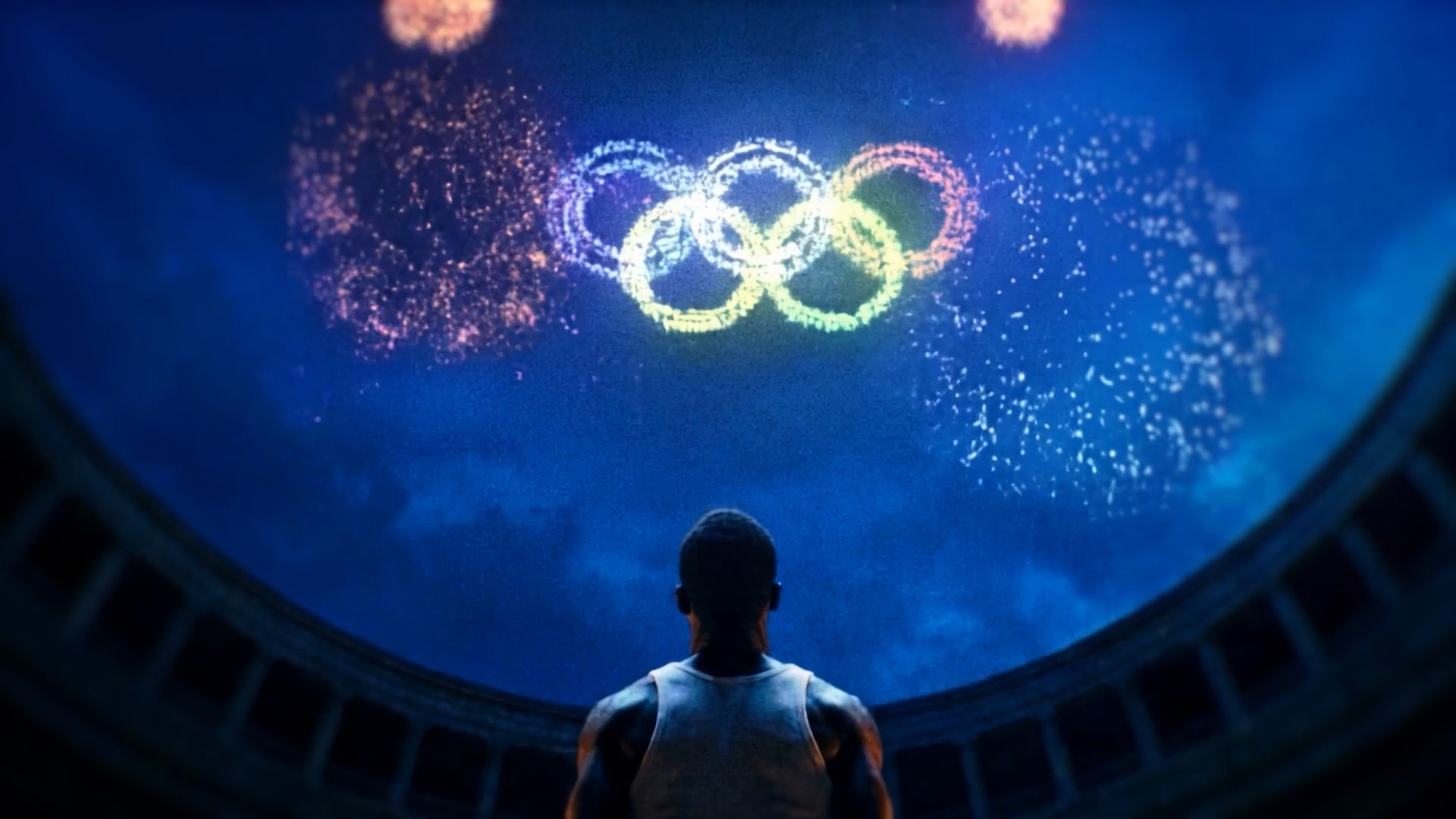Plan de clôture du film : l'athlète face aux anneaux olympiques en feu d'artifice dans le dôme